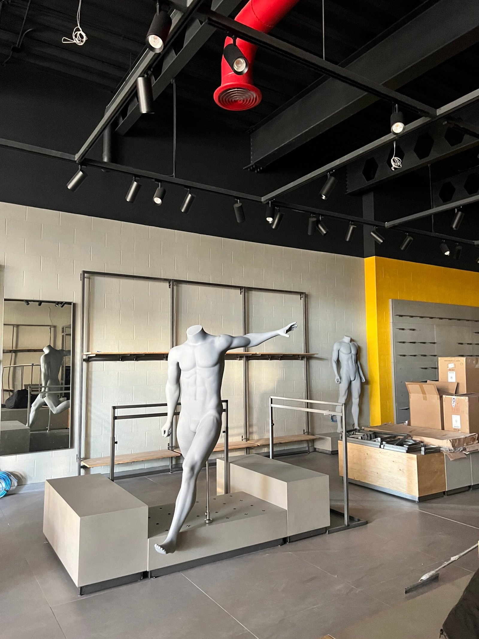 Instalación de estructuras de exhibición, maniquíes y rieles de iluminación en un local comercial en proceso de adecuación.