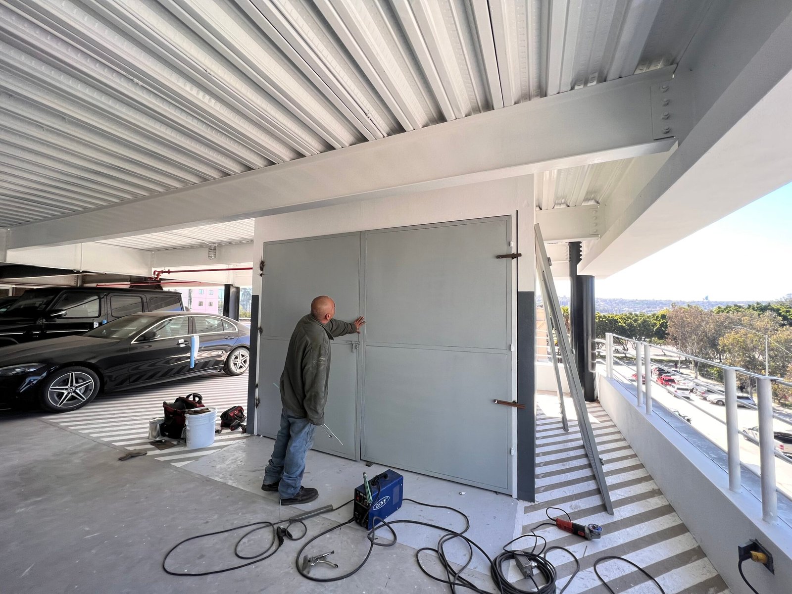 Hombre de espaldas trabajando con soldadura en una puerta de acero en un proyecto comercial de Mercedes Benz en Tijuana